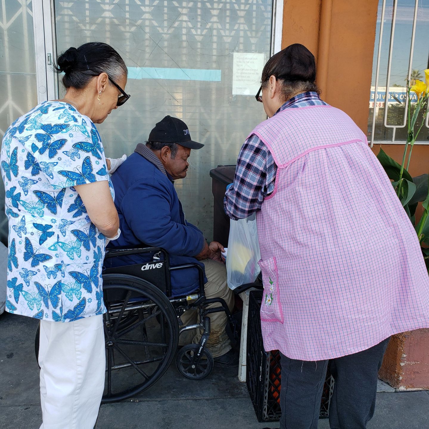 Angie Austria (left) and Maria Isabel Velasco (right) give food to a man named Enrique (Amairani Hernandez_UT).jpg